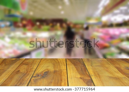 blurred image wood table and abstract generic supermarket people walking shopping