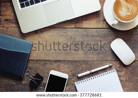 Office wood table with notepad,laptop smartphone pen mouse and coffee cup. View from above with copy space