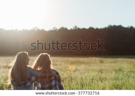 Two young women hugging at sunset.  Back view. Best friends Royalty-Free Stock Photo #377732716