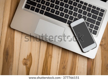 Laptop computer and smart phone on wood table background. top view