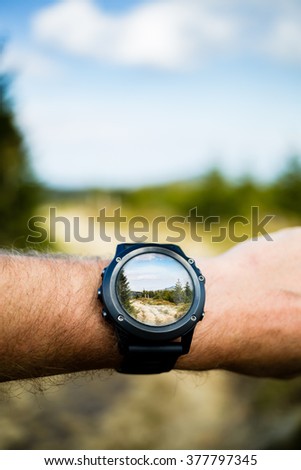 Wearable technology, man taking photo with smartwatch camera in mountains. Smart watch photography with camera app application in beautiful inspirational landscape. Modern electronics in use.
