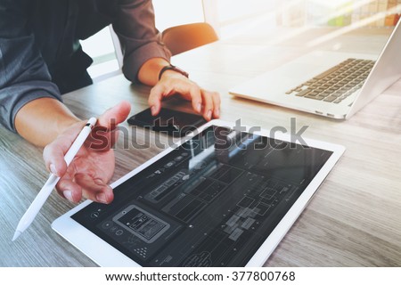 Website designer working digital tablet and computer laptop and graphics design diagram on wooden desk as concept