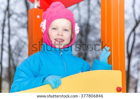 Cute, little girl in the playground in winter day