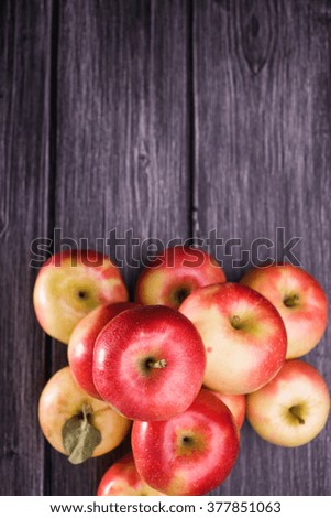 Top view of pile of tasty smooth homegrown fresh red yellow apples on grey wooden timber background, vertical photo