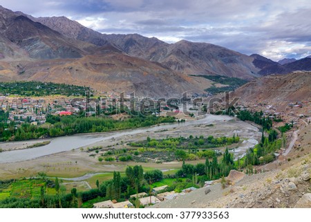 Top view of Indus river and Kargil City valley with Himalayan mountains and blue cloudy sky in background, Leh, Ladakh, Jammu and Kashmir, India