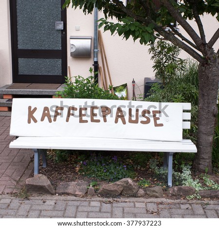The inscription " coffee break " in German on the bench near the house