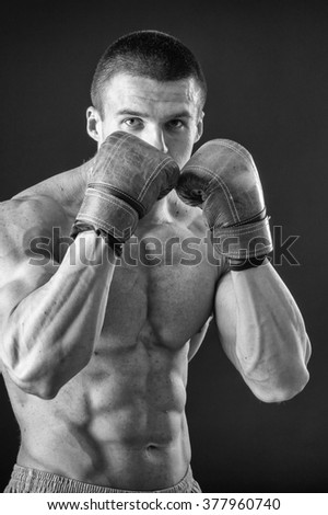The man in boxing gloves. Young Boxer fighter over black background. Boxing man ready to fight. Boxing, workout, muscle, strength, power - the concept of strength training and boxing