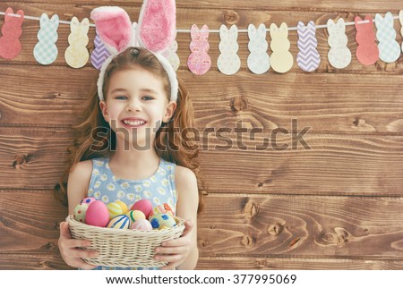 Cute little child girl wearing bunny ears on Easter day. Girl holding basket with painted eggs. Royalty-Free Stock Photo #377995069