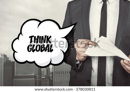 Think global text on speech bubble with businessman holding paper plane in hand
