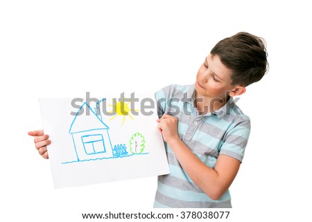 A ten years boy is holding a picture of a village house, isolated on white background