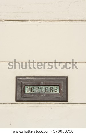 Verdigris Brass Letter Box in an off white wall vertical. Brass mail box in a stucco wall with space for copy text