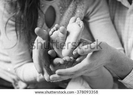 parents hands holding baby's feet, black and white photo