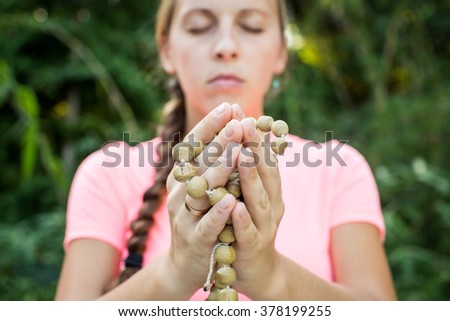 Woman holds a rosary in his hands and pray