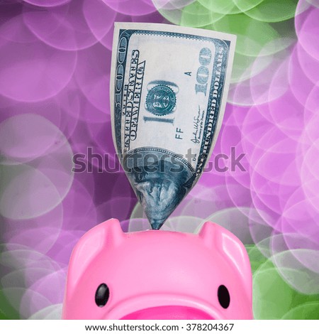 Putting dollar in funny piggy bank.

