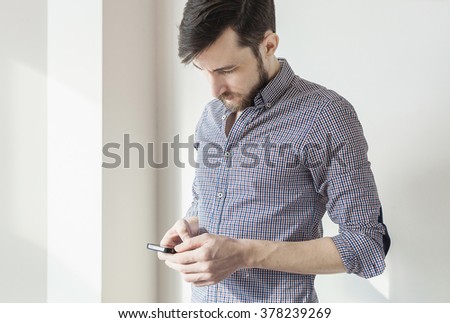 Indoor portrait of modern young man with mobile phone