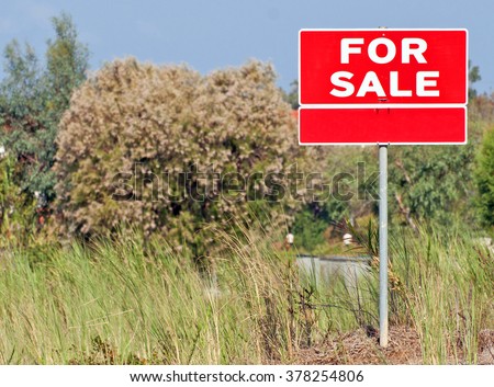 Land for sale sign in empty field 