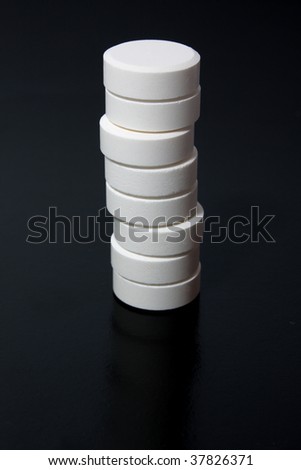 heap of white tablets on black background