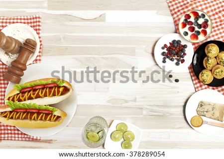 Hot dog with cheese, crackers, lemon pepper and berries as well put on a plate on the table view