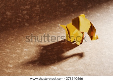 A yellow origami elephant isolated on craft paper background.