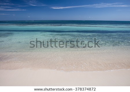 The warm waters of the Caribbean Sea wash against a remote, sandy beach off the coast of Belize. Royalty-Free Stock Photo #378374872