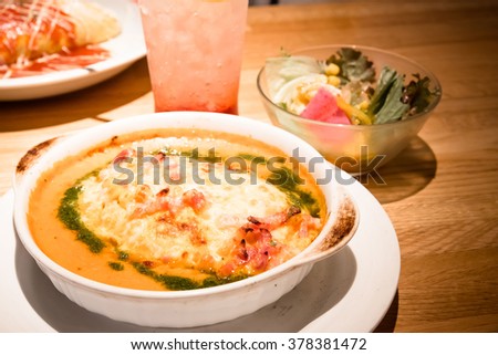 Soda drinking and Golden lasagna with meat, tomatoes, cheese sauce and pasta in alternating layers on a wooden board garnished with basil - warm and dark tone.