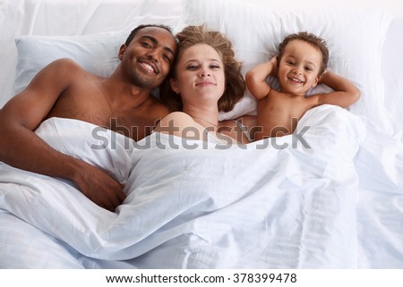 Happy family on white bed in the bedroom. Concept of cheerful American family