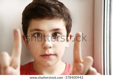 preteen handsome boy play squinting trick with his eyes and fingers close-up portrait Royalty-Free Stock Photo #378400942