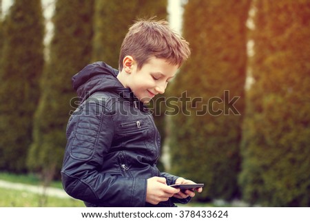 Happy little boy playing on tablet outdoor in sunset