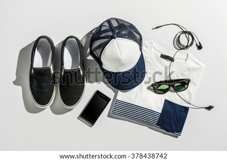 Overhead view of men's casual outfits on gray paper board background, Essential vacation items