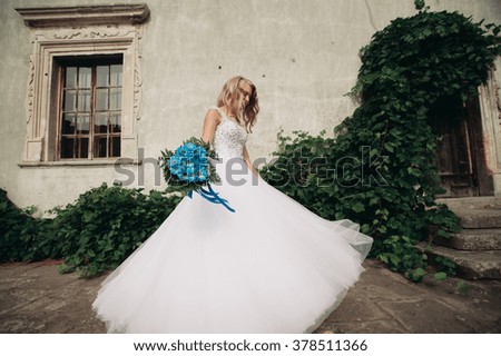 Beautiful young blond bride with bridal bouquet dancing on the background gorgeous plants