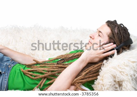 Young adult with dreadlocks and headphones lying on a couch