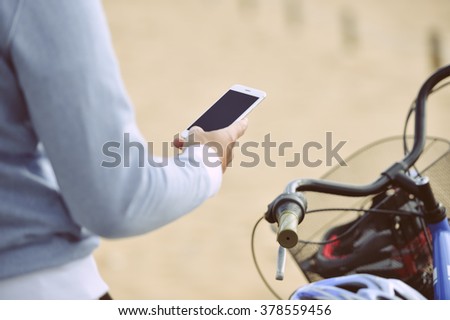 Man with bicycle holding mobile smart phone in hand with blank screen, outdoors background