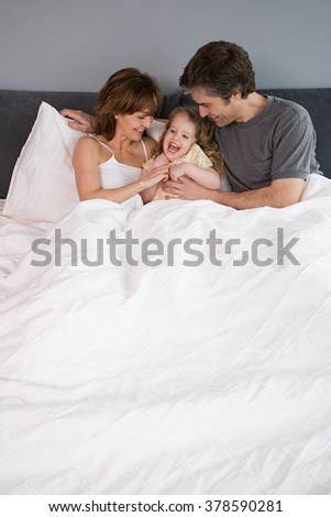 mother and father tickling their daughter