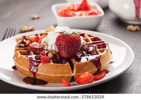 Whole wheat Belgium waffle topped with boysenberry syrup, whipped cream, walnuts, and freshly chopped strawberries horizontal shot Royalty-Free Stock Photo #378613054
