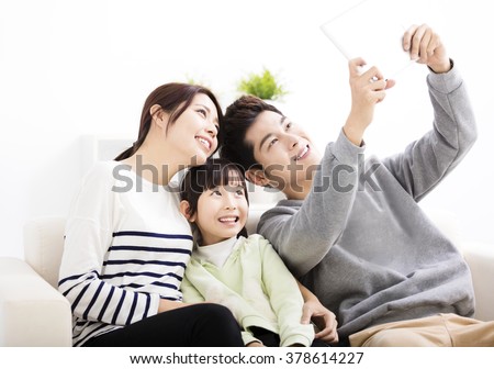 Happy young family taking selfies on sofa