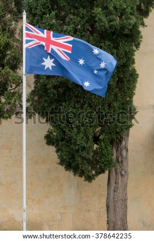 Australian flag flying in breeze with old building in background