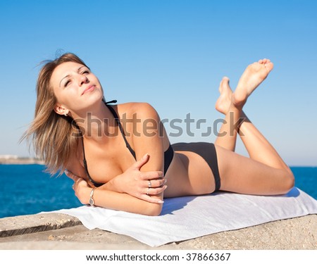 Attractive smiling girl in black swimsuit on seashore