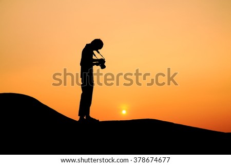 Silhouette picture of a man prepare to take photograph in sunset