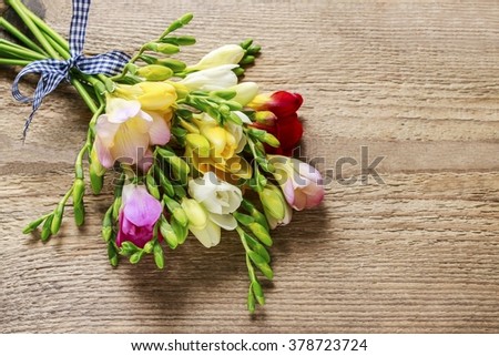 Colorful freesia flowers on wooden background, copy space