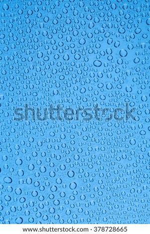 Blue background drops of water on clear glass.
