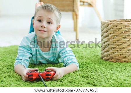 Cute boy playing video games at home