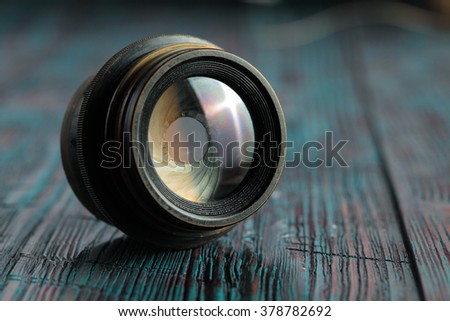 Old lens from old camera on the wooden table