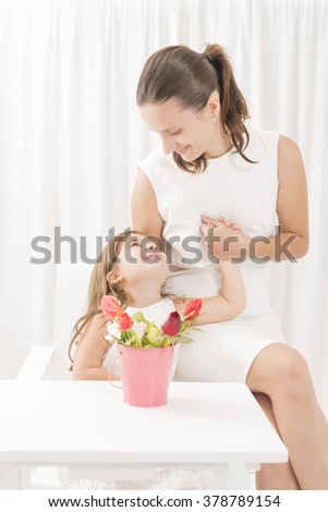 Smiling mother getting flowers from her daughter on mother's Day.Toddler girl giving flowers to her mom on mother's day. Happy family concept