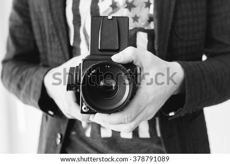 Hands of young photographer holding old medium format camera , black and white