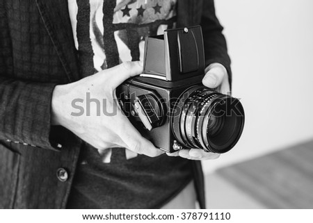 Hands of young photographer holding old medium format camera , black and white
