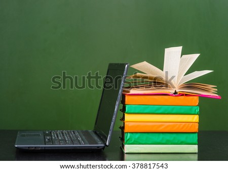 Books and notebook near empty green chalkboard. Sample for text 