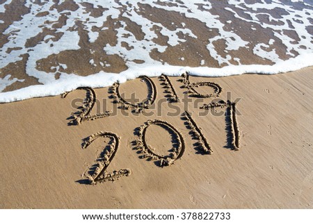 New Year 2017 is coming concept - inscription 2016 and 2017 on a beach sand, the wave is almost covering the digits 2016 Royalty-Free Stock Photo #378822733