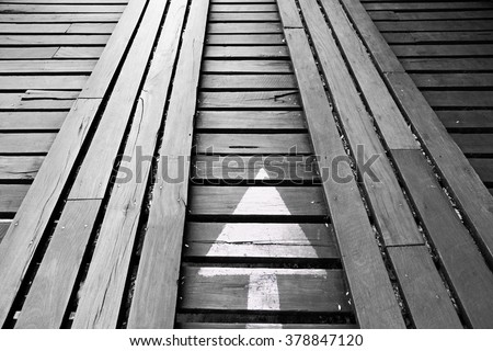 white arrow direction sign on wooden walkway, back and white photo