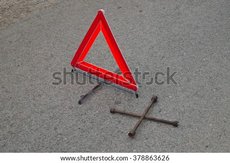 Reflective car warning triangle and tool on the road. Driving and safety themes