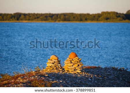 Funny piles of pebble stone on sea sunset background